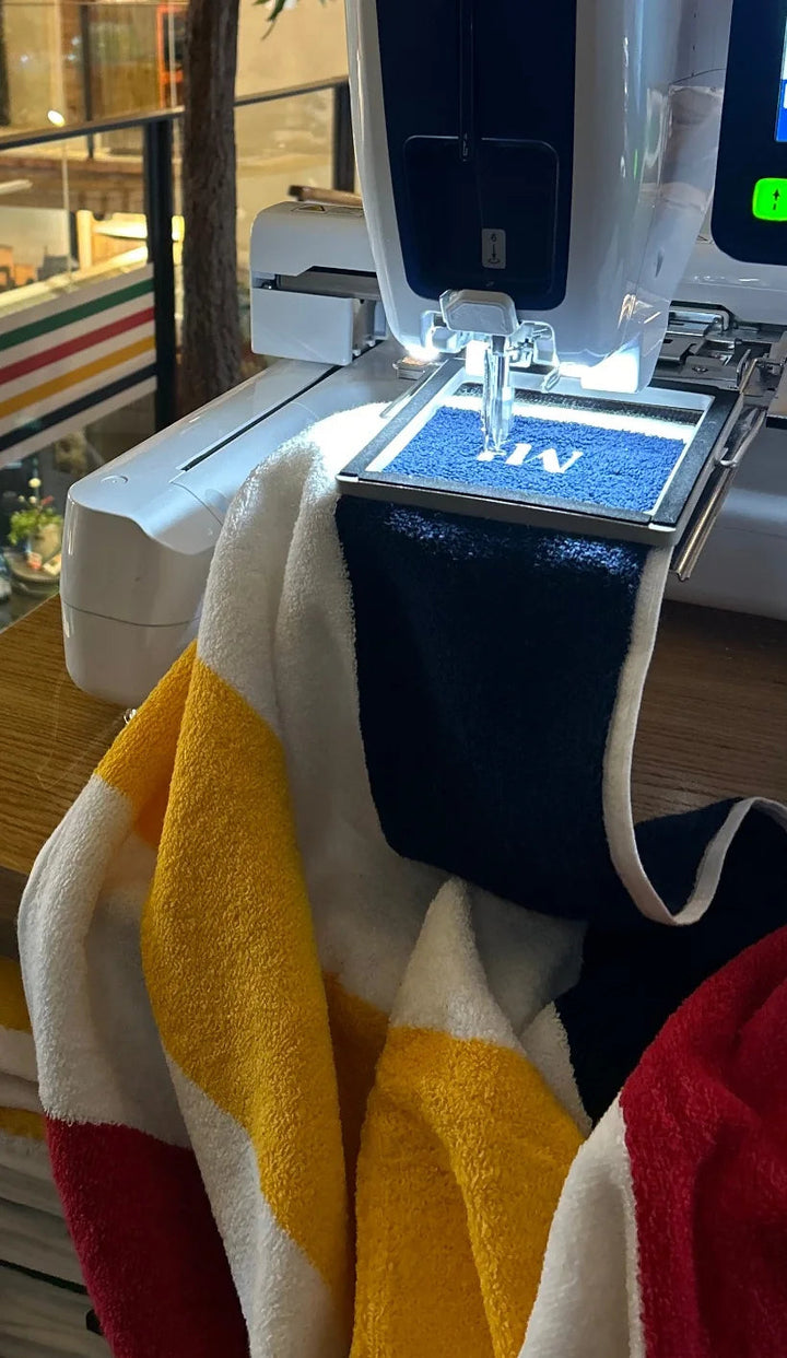 A striped towel in a hoop with white monogram stitching