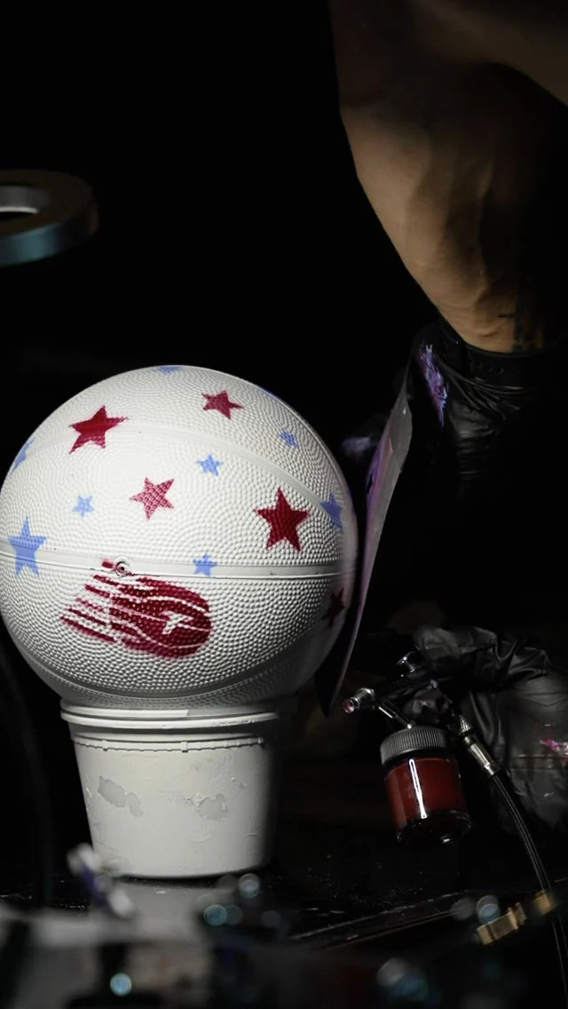 An artist airbrushing a Toronto Tempo basketball