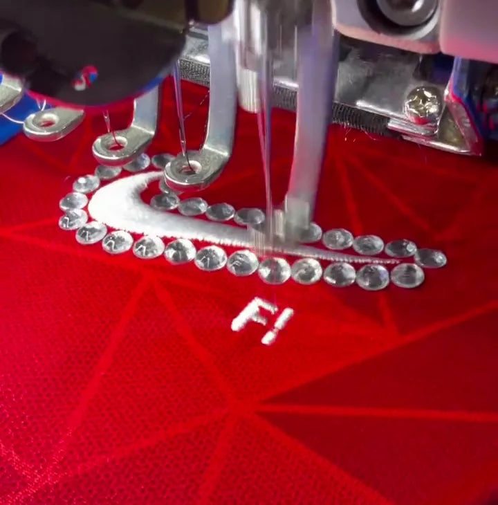 Lettering being embroidered onto a red jersey at an upcycling workshop