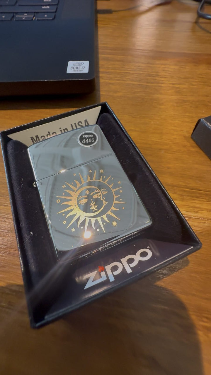 Chrome lighter with a gold sun and moon design laser-engraved on the front