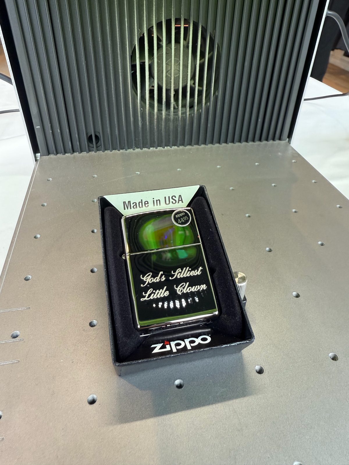 Boxed lighter with script text laser-engraved on its front, sitting on the laser bed
